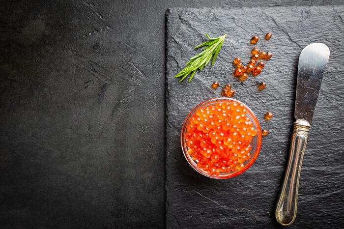 Delicious red caviar on black slate background, top view
