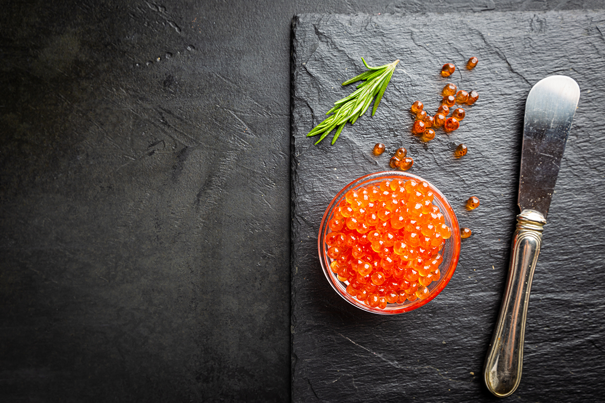 Delicious red caviar on black slate background, top view