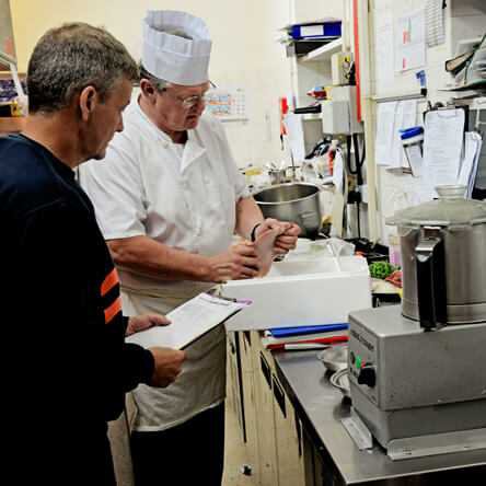 two men querying with a clipboard in their hand