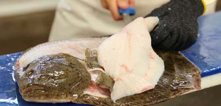 skilled fishmonger cutting a fish fillet piece