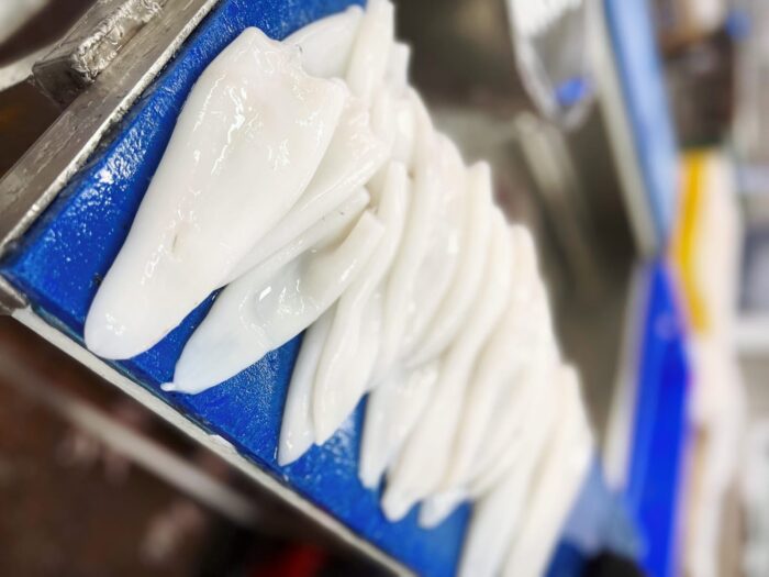 Fresh squid fillets on a blue chopping board
